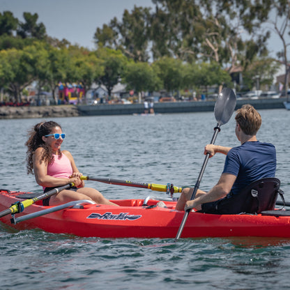 Couple rowing a red RowYak face-to-face tandem kayak on a lake