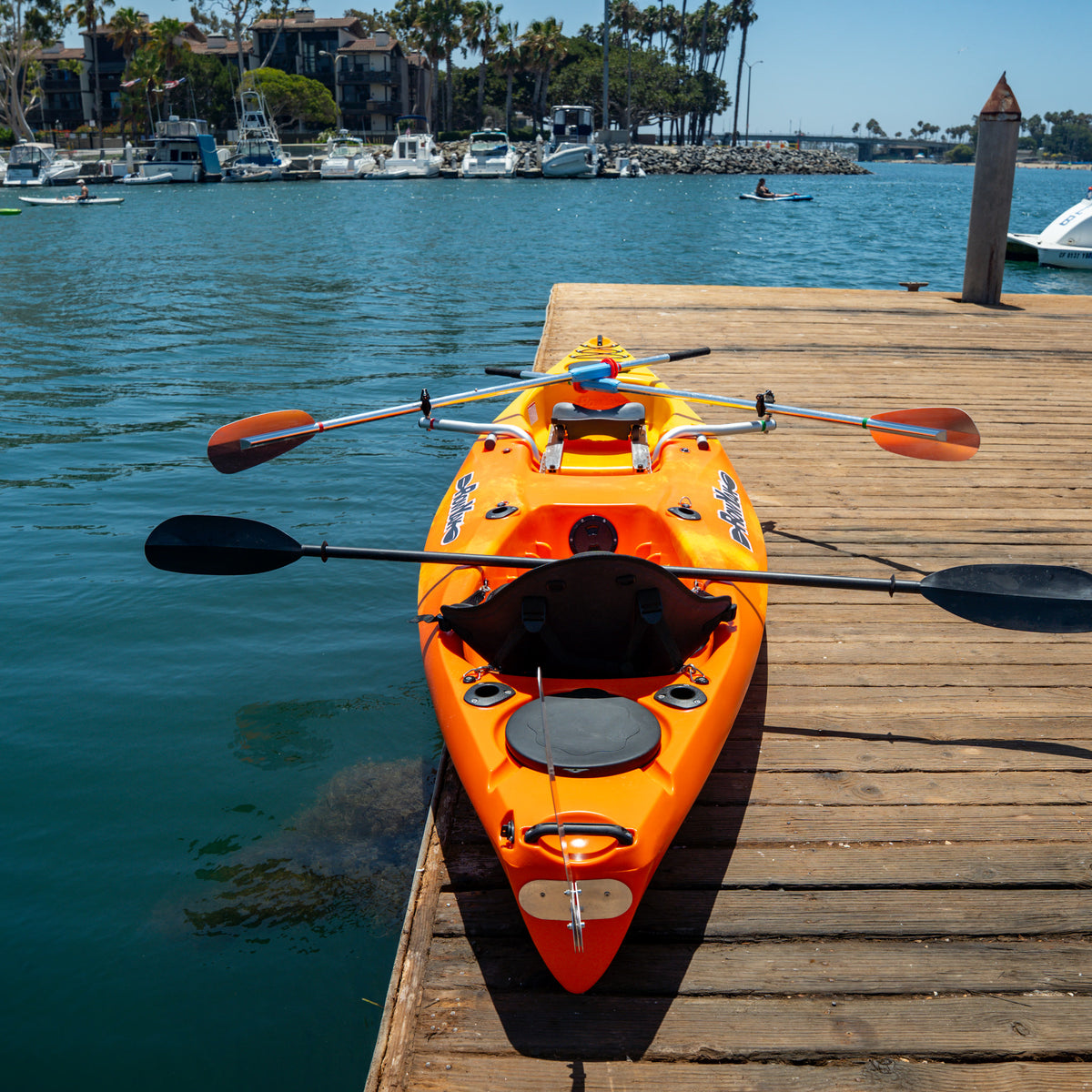 Top view of a sunset RowYak tandem kayak beside a dock