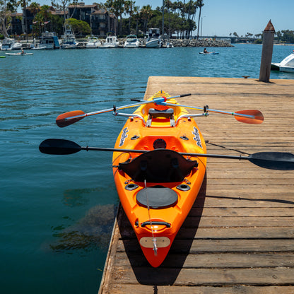 Top view of a sunset RowYak tandem kayak beside a dock