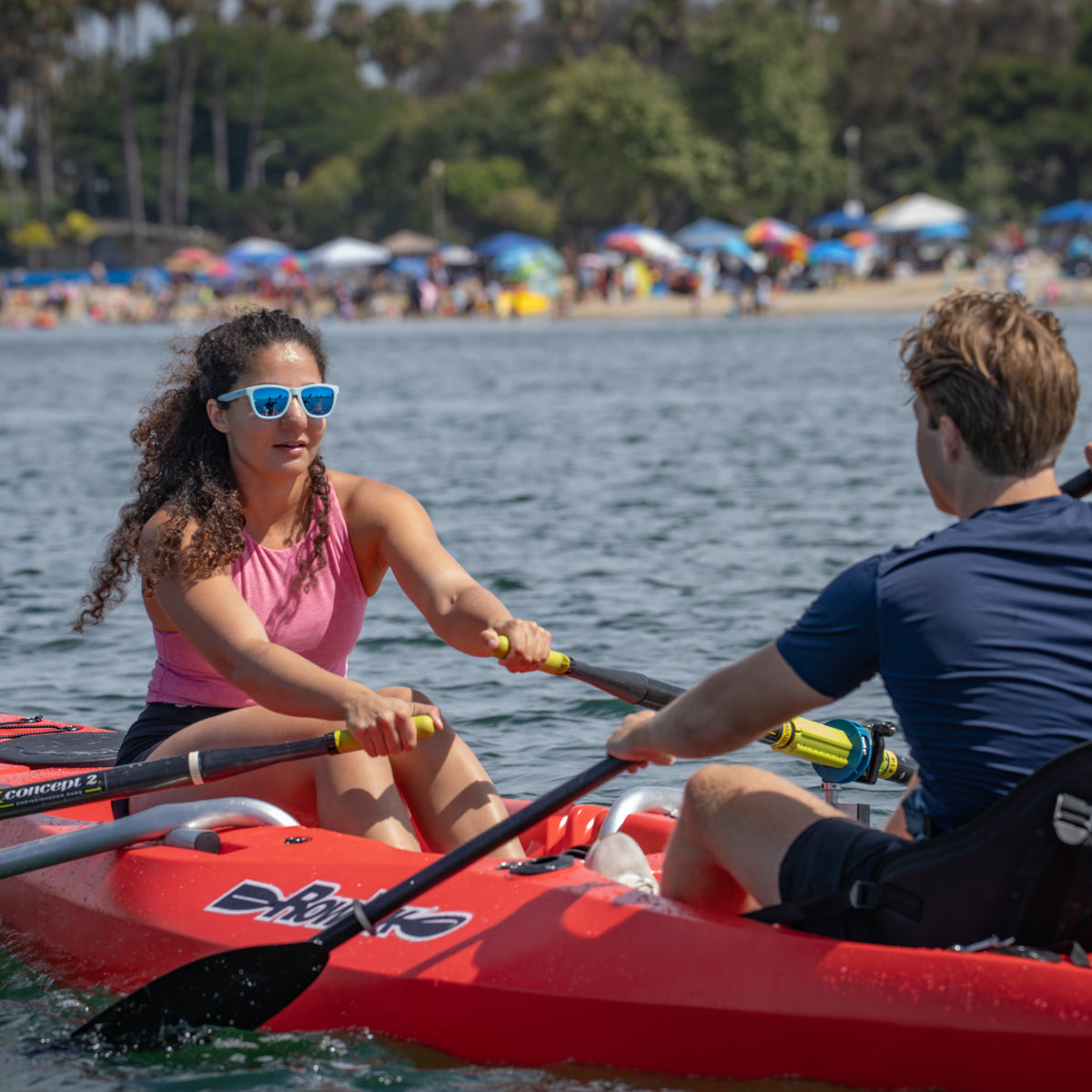 Couple using the rowing system on a red RowYak tandem kayak