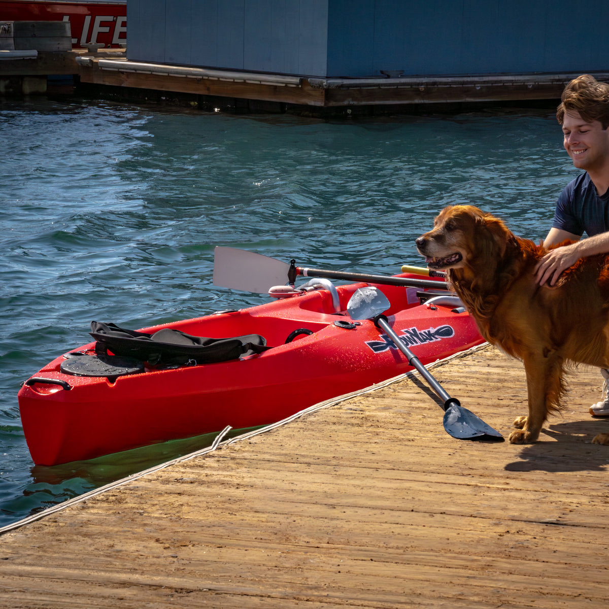 Red RowYak tandem kayak at a dock with a paddler and dog
